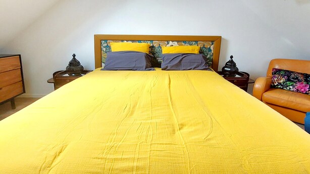 A bed with a yellow bedspread and pillows, a wooden headboard, and a nightstand with a lamp. - Gorgeous home in Huisnes sur mer with WiFi (Huisnes sur mer)