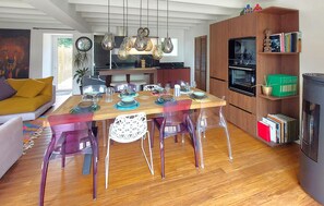 A modern kitchen with wooden cabinets, a dining table set for four, and a bookshelf filled with books. - Gorgeous home in Huisnes sur mer with WiFi (Huisnes sur mer)