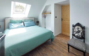 Ein Schlafzimmer mit einem Bett, einem Sessel, einer Holztür und einem Fenster.