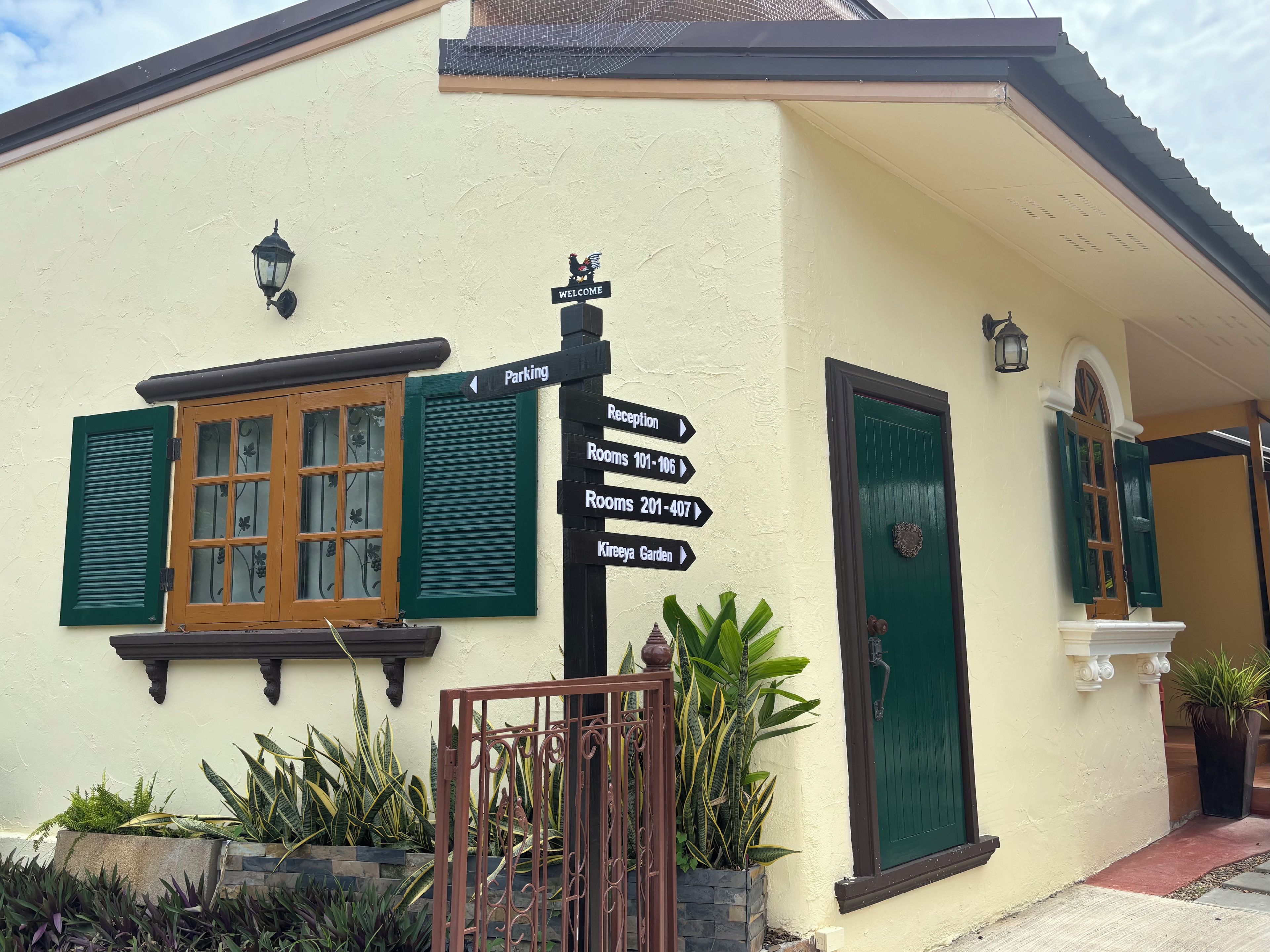 A building with a signpost indicating directions to rooms, a reception, and a garden.