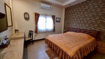 A bedroom with a bed, a desk, a chair, a clock, and a window with curtains.