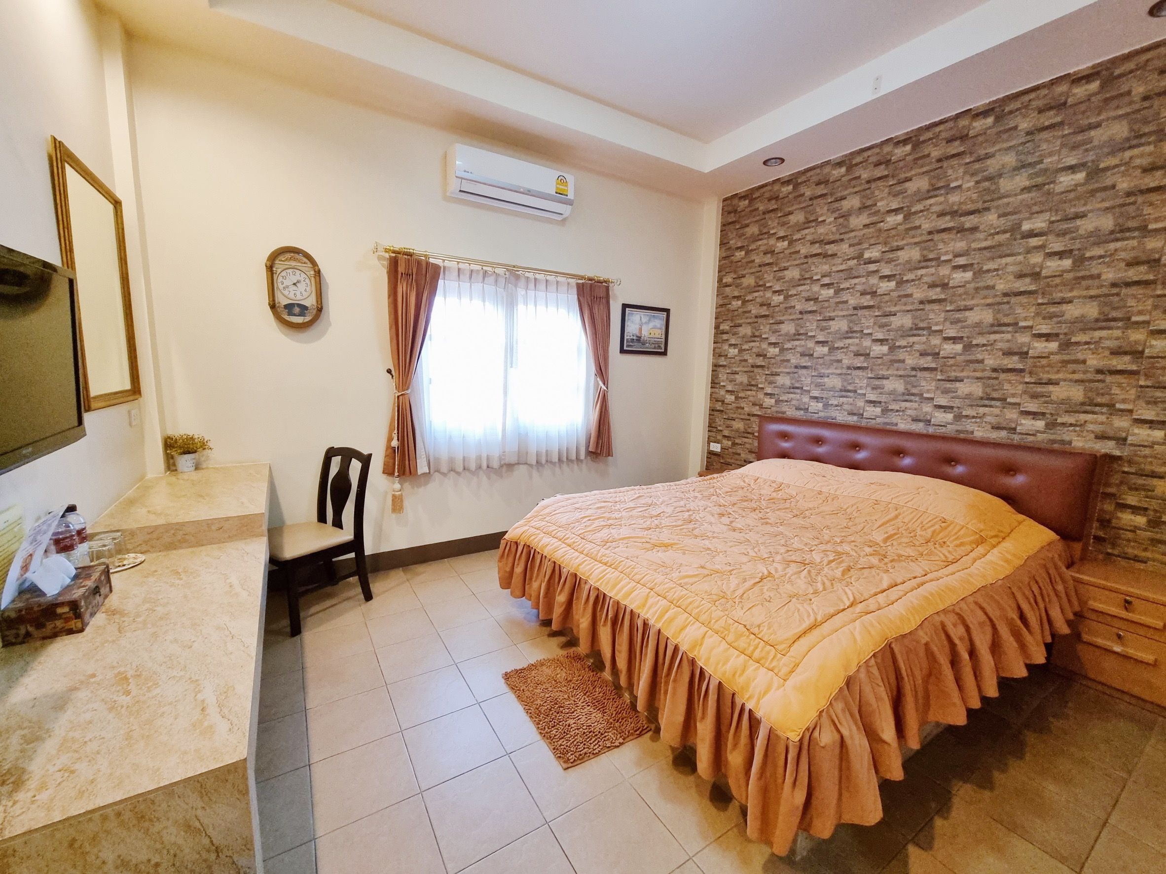 Un dormitorio con una cama, una silla, un reloj y una ventana con cortinas.
