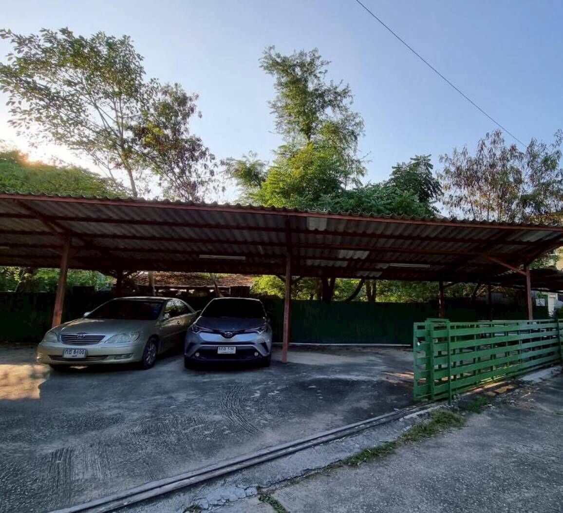Área de estacionamento coberta com dois carros estacionados sob uma cobertura de metal.