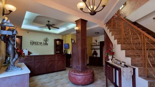 Vestíbulo de hotel con mostrador de recepción, una columna de madera grande, una escalera y una araña.
