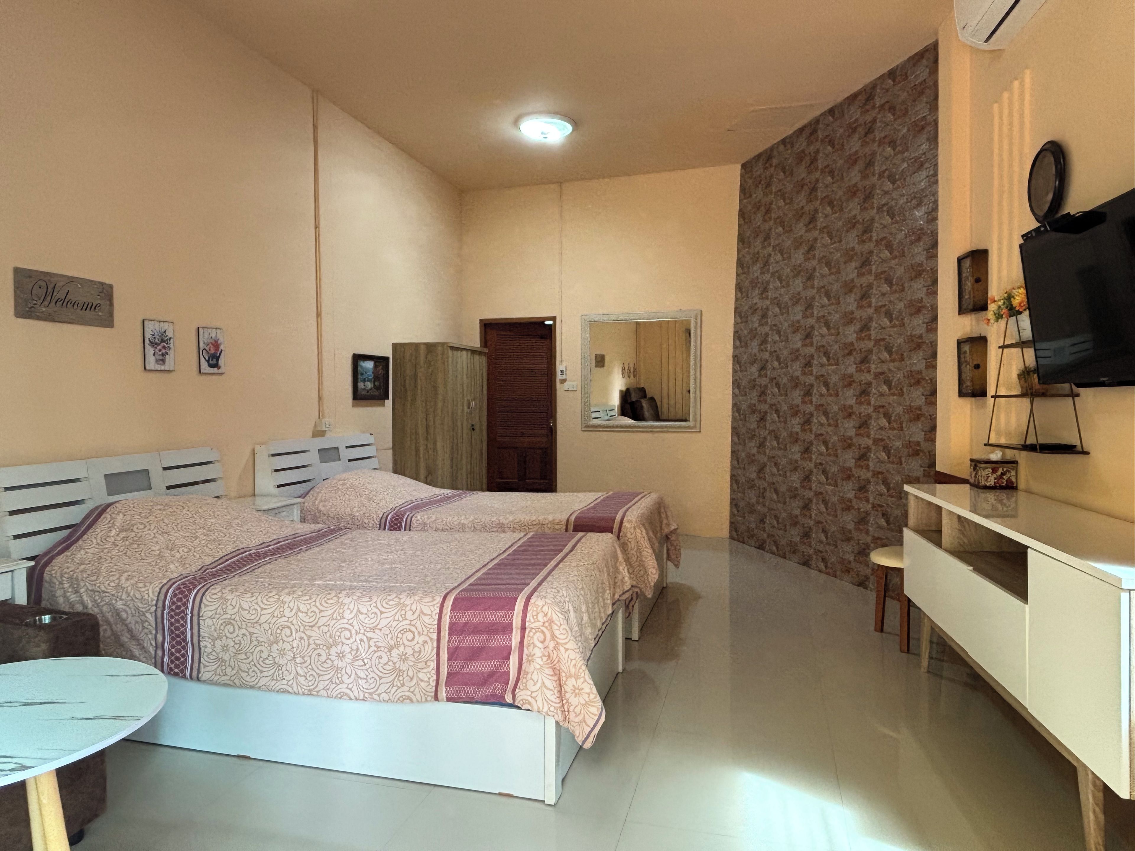 Un dormitorio con dos camas, un escritorio, un espejo y un televisor.