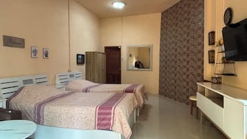 Un dormitorio con dos camas, un escritorio, un espejo y un televisor.