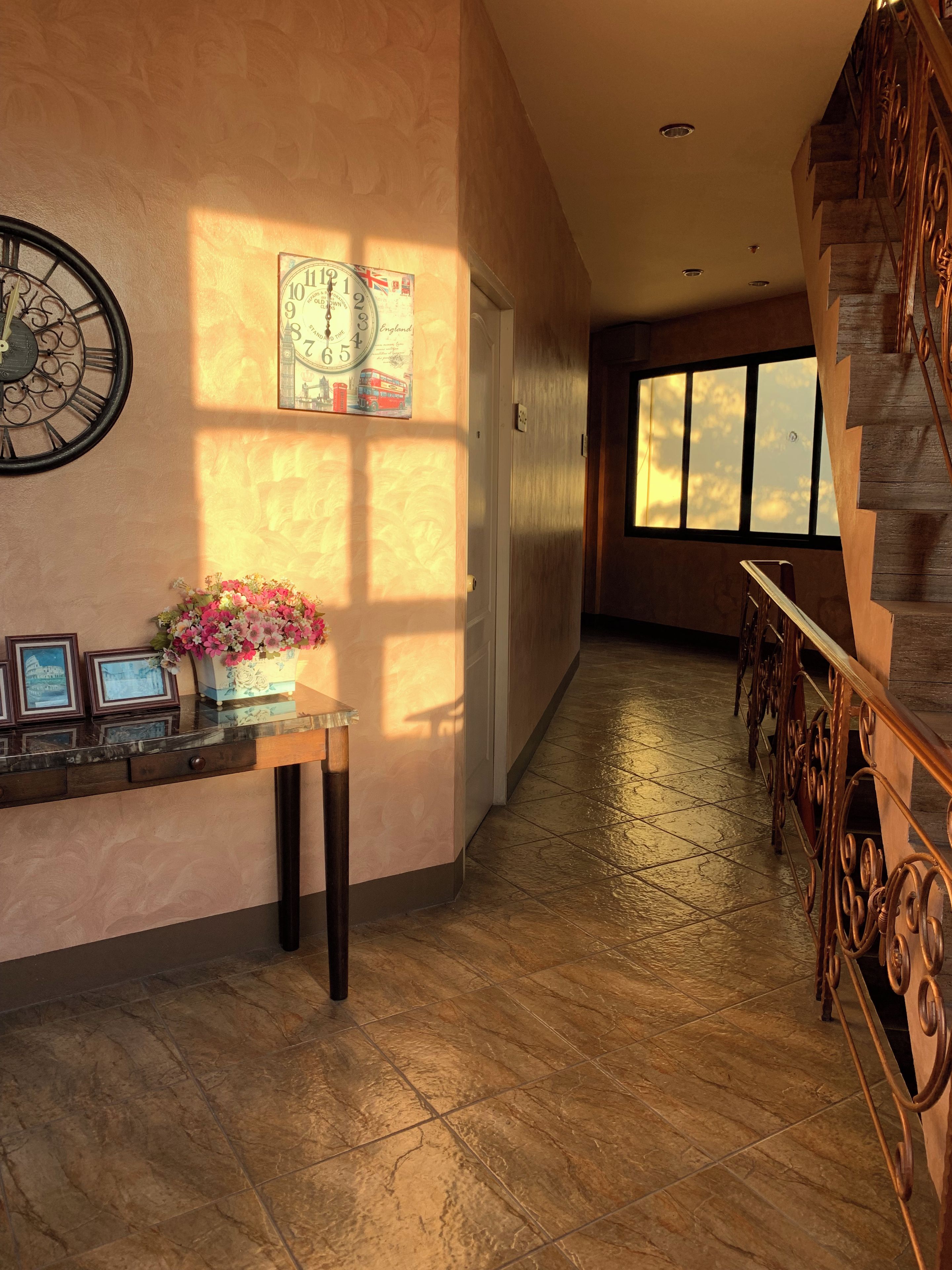 A hallway with a clock, a framed map, and a staircase.