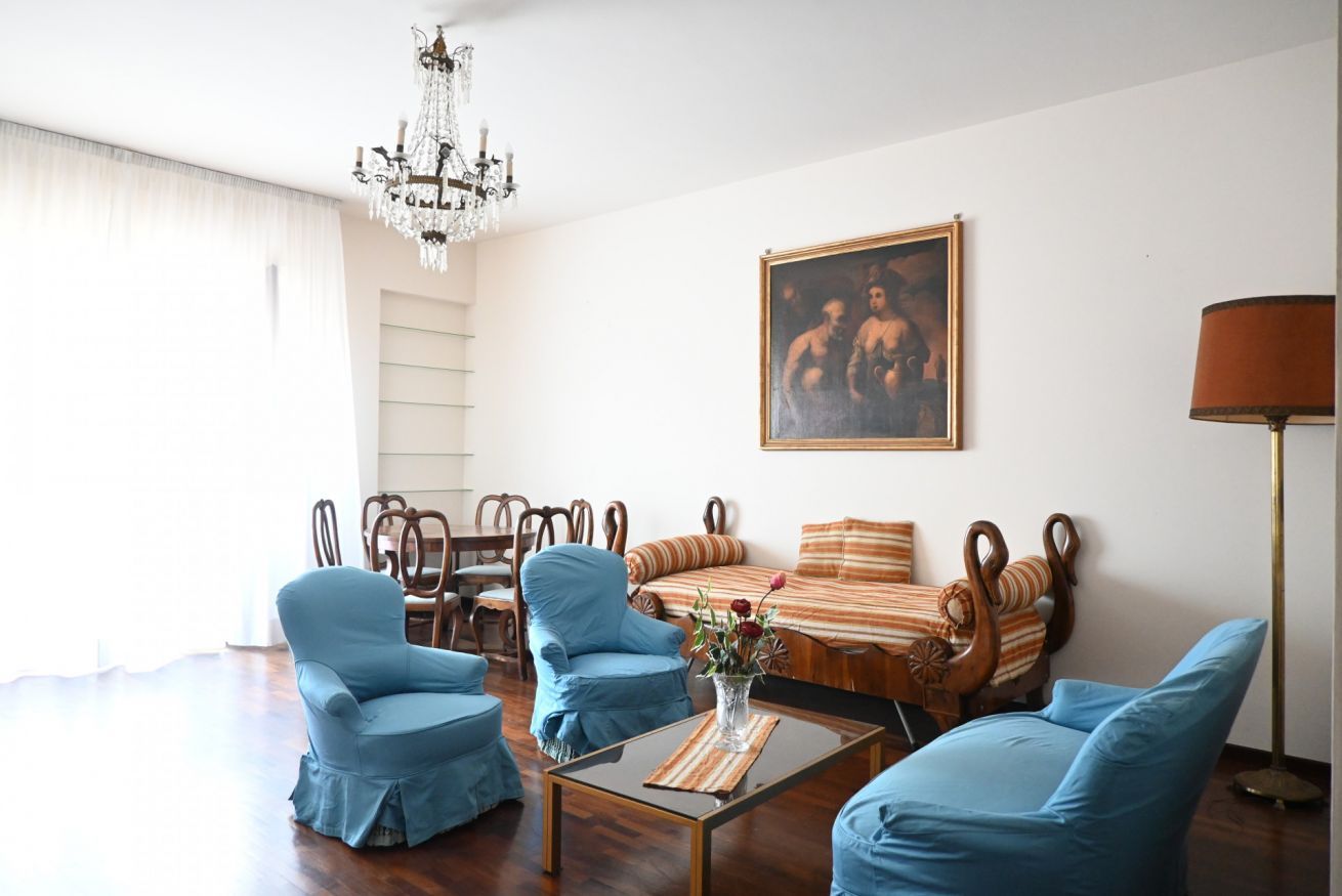 Ein Wohnzimmer mit einer Deckenleuchte, einem Gemälde, einer Sofagarnitur und einem Couchtisch.