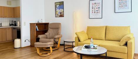 Un salon comprenant un canapé, un fauteuil, une table basse et une bibliothèque.