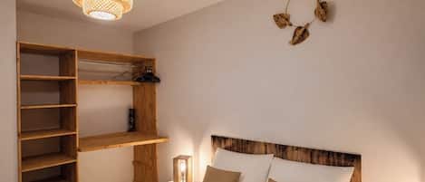 Un dormitorio con cama, estanterías de madera, una lámpara colgante y un adorno en la pared.