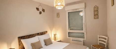 A neatly arranged bedroom with a bed, bedside tables, a chair, and a window with blinds.