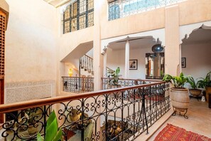 A spacious interior with a high ceiling, a staircase with ornate railings, and multiple levels with balconies. - Riad Azura & Rooftop  (Marrakesh)