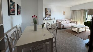 Una sala de estar moderna con un sofá, una mesa de comedor con sillas y una zona de cocina.