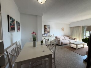 Ein modernes Wohnzimmer mit einer Couch, einem Esstisch mit Stühlen und einer Küchenzeile.