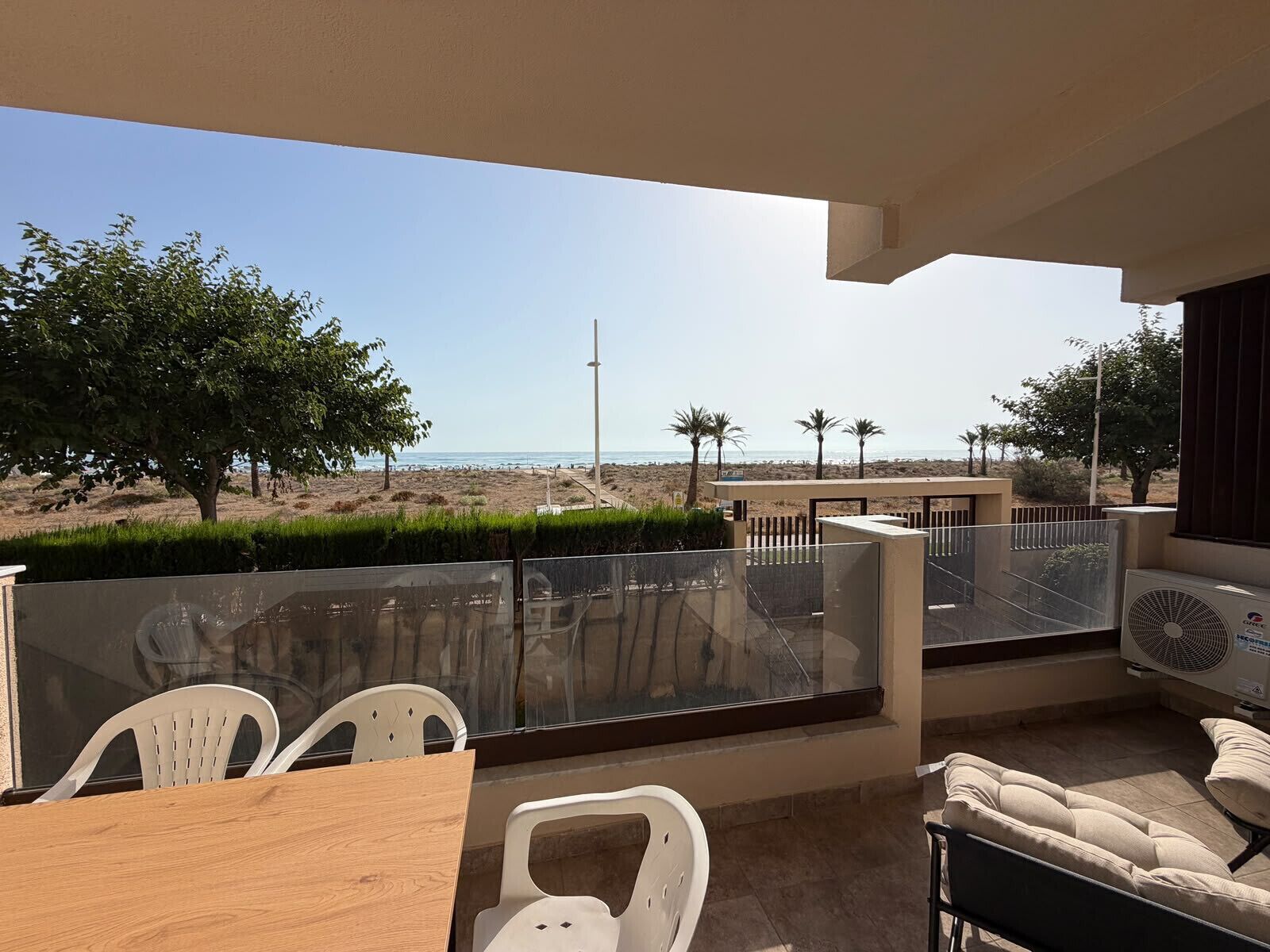 Een balkon met uitzicht op het strand, een tafel met stoelen en een bank.