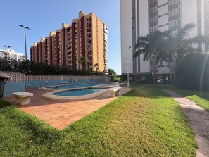 Edificio residencial con piscina y césped cuidado.