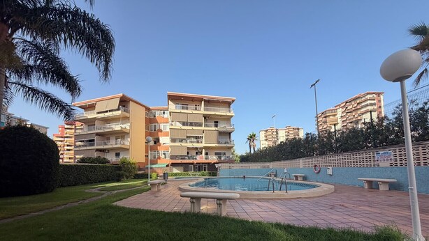 Un edificio residencial con varios balcones, una piscina y un jardín bien cuidado.