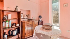 Eine Küche mit Holzausstattung, einem Tisch mit Blumenmuster-Tischdecke und einem Fenster mit Blick auf eine Mauer.