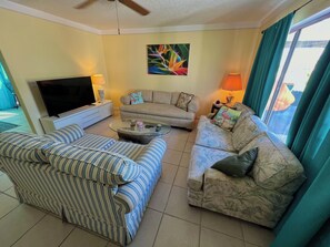 A living room with two sofas, a coffee table, a TV, and a painting on the wall. - Cute House in East Englewood (Port Charlotte Thorman Rd)