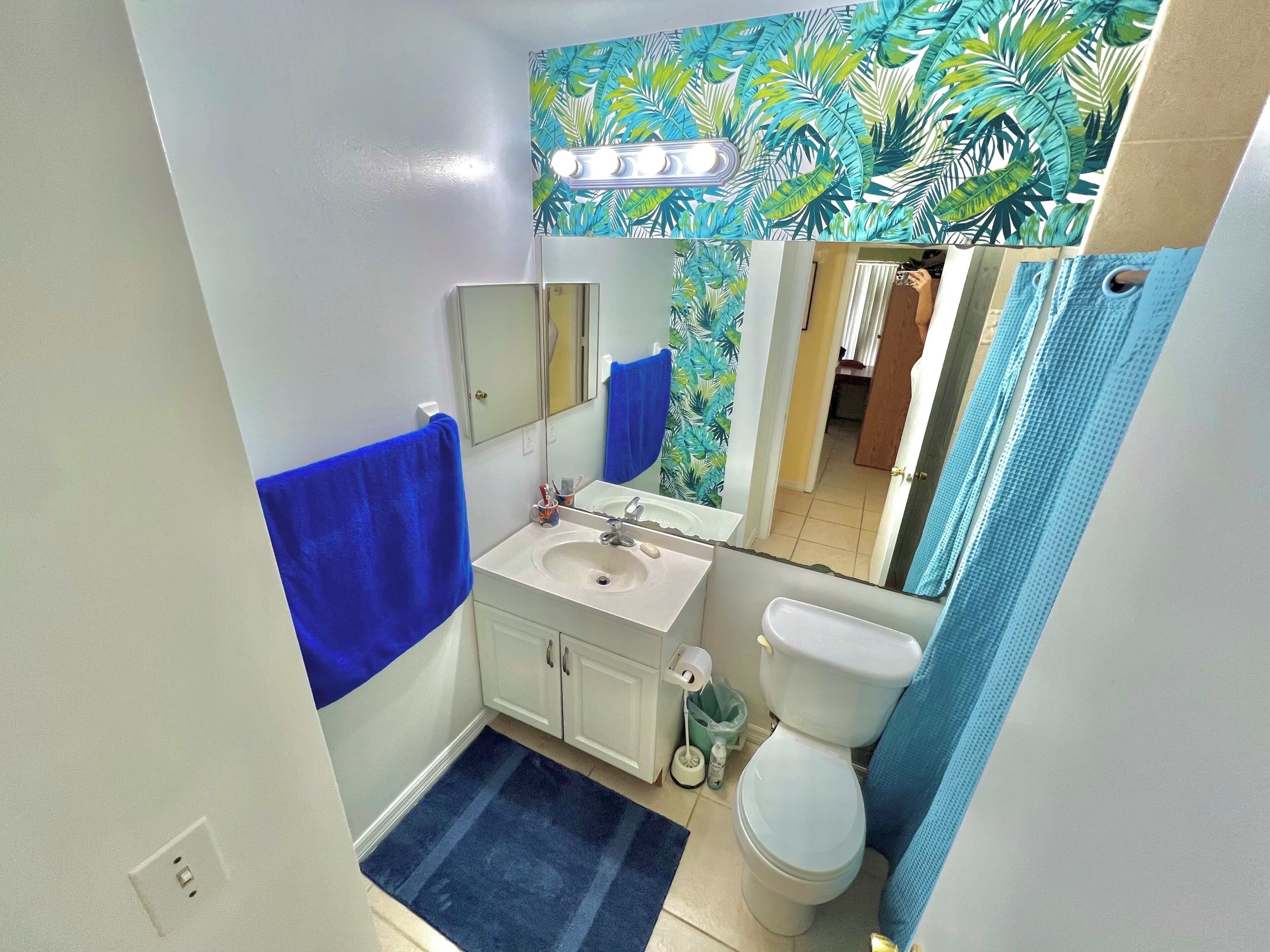 Ein Badezimmer mit Waschbecken, Spiegel, Toilette und blauem Handtuch.