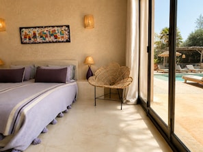 Habitación de hotel con una cama, una silla, una lámpara y vistas a una piscina.
