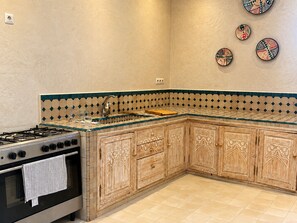Una cocina con estufa a gas, horno y pileta. Hay platos decorativos en la pared.
