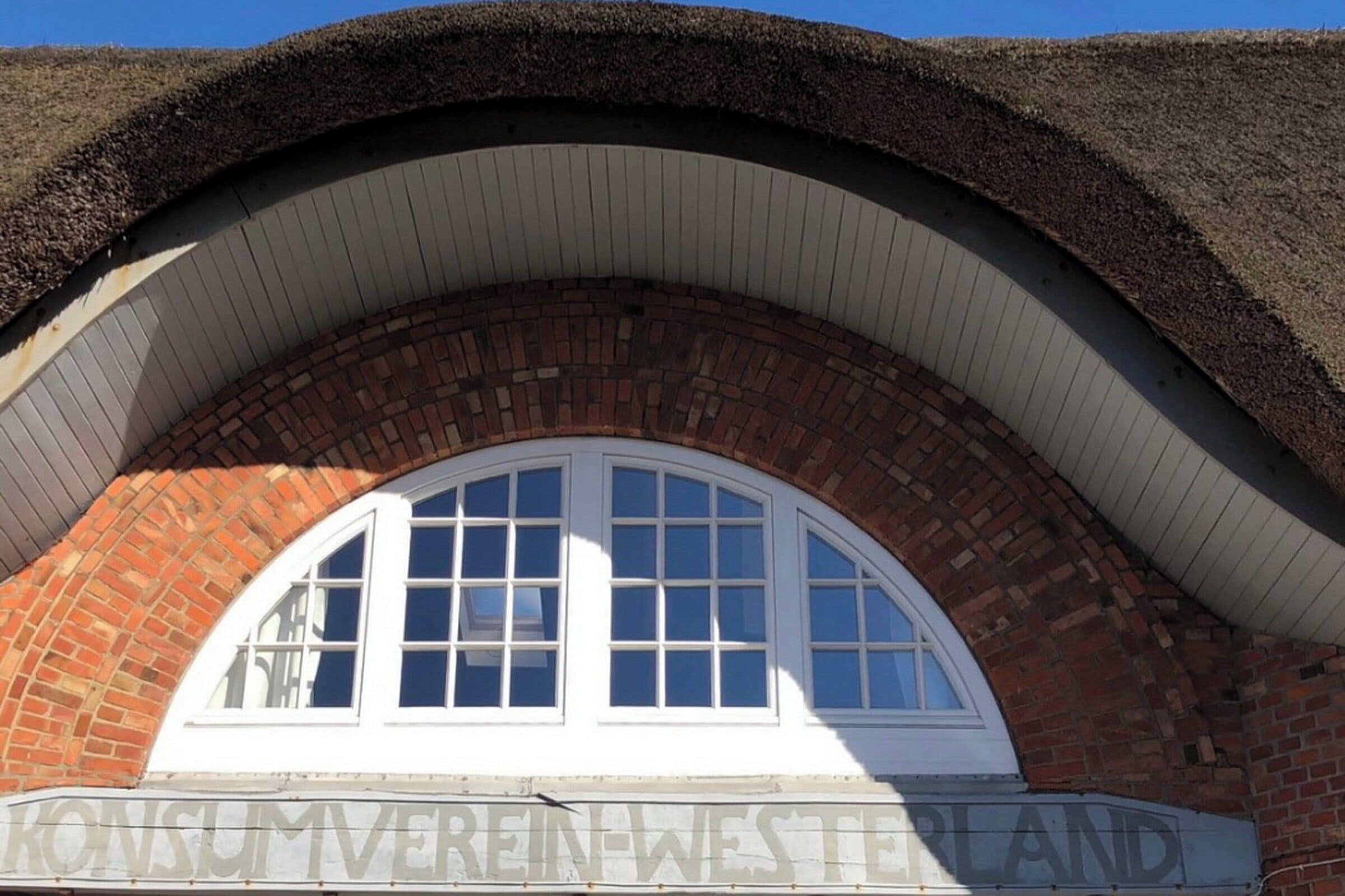 Un bâtiment à la façade en briques et doté d’une fenêtre en arc surmontée d’un cadre blanc.