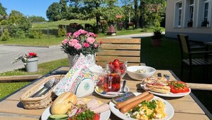 A picnic table with food, a basket, and a vase of flowers.