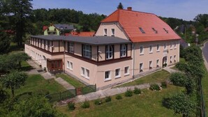A two-story building with a red-tiled roof, multiple windows, and a garden area.