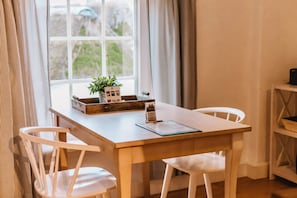 Spiseområde med et træbord, hvide stole, en lille plante og en menu på bordet.