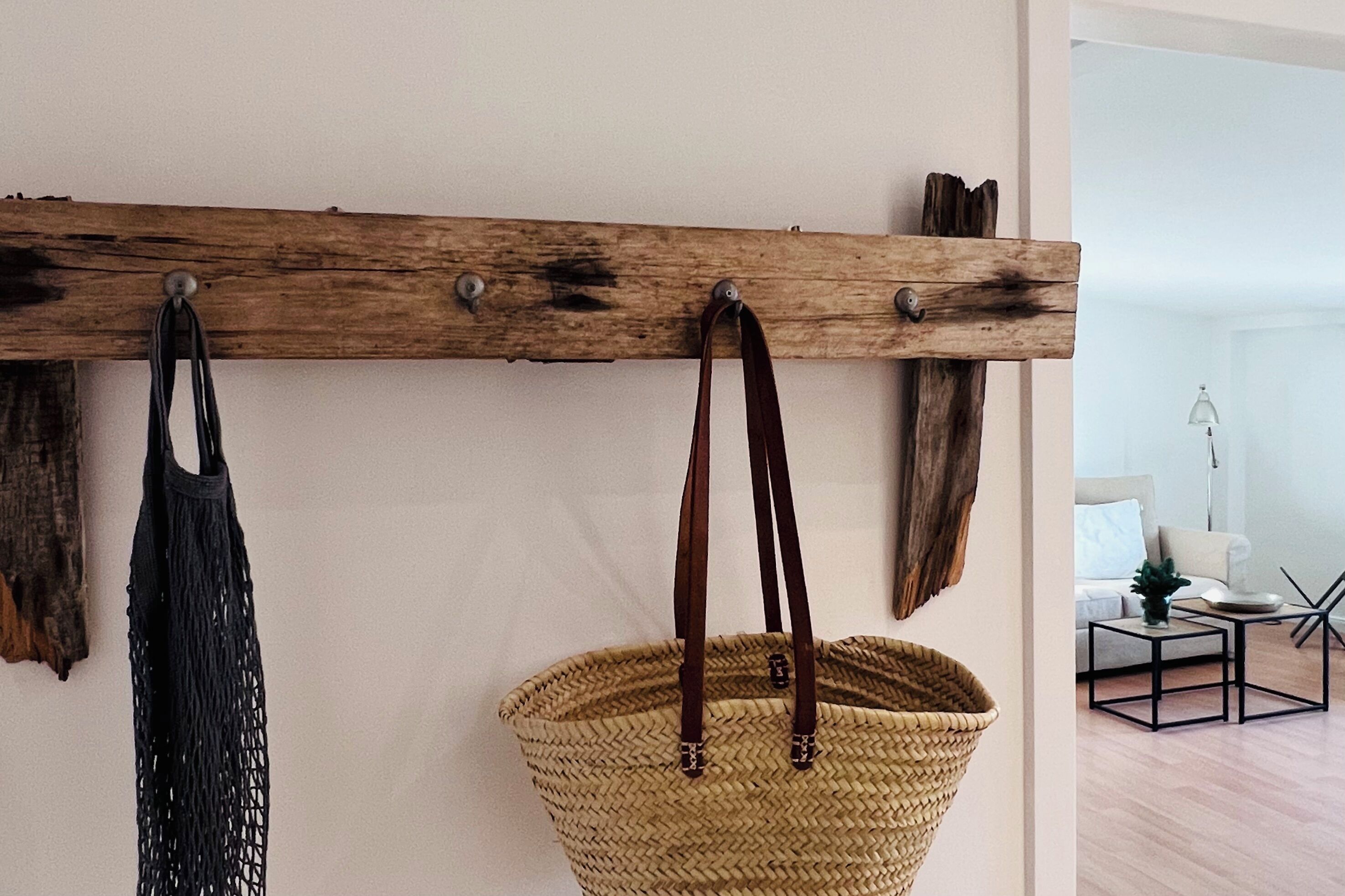 Ein an der Wand befestigtes Holzregal mit zwei Taschen und einem gewebten Korb.