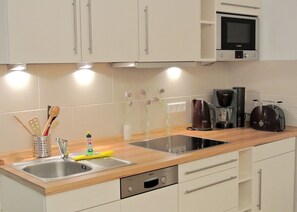 A modern kitchen with two sinks, a Bosch dishwasher, a coffee maker, and a toaster. - Cozy Apartment at the Alter Konsumverein on Sylt – A Relaxing Vacation (Sylt)