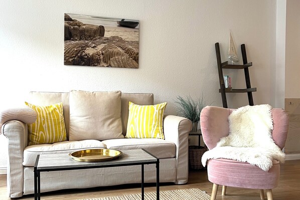 A living room with a sofa, a coffee table, a chair, and a ladder against the wall. - Vrbo Property (Sylt)