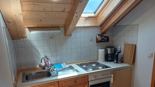 A kitchen with wooden cabinets, a sink, a stove, and a skylight.