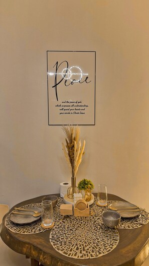 A table with a decorative centerpiece, a framed inspirational quote, and a vase with dried plants. - Shore 2 Cozy Staycation, Pool View, Near MOA and NAIA Airport w/ Netflix (Pasay City)