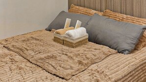 A bed with a textured blanket, two pillows, and a woven basket. - Shore 2 Cozy Staycation, Pool View, Near MOA and NAIA Airport w/ Netflix (Pasay City)
