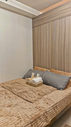 A bed with a textured blanket, two pillows, and a woven basket. - Shore 2 Cozy Staycation, Pool View, Near MOA and NAIA Airport w/ Netflix (Pasay City)