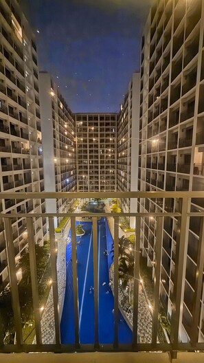 Un immeuble de grande hauteur, doté de nombreux étages, chacun ayant des balcons, et une cour intérieure agrémentée d’un élément aquatique bleu.