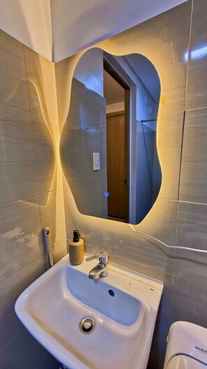 Ein Badezimmer mit Waschbecken, Spiegel und einer Tür zu einem anderen Raum.