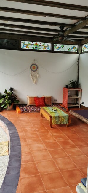 Ein überdachter Patio-Bereich mit einer Couch, einem Tisch und einer Traumfänger-Dekoration.