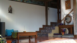 A room with a wooden bench, a small table with a cloth, a wall-mounted decorative item, and a staircase with a mirror. - Villa Cempaka Water Portal Ubud (Gianyar)