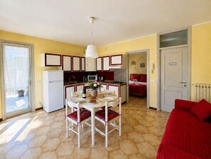 A compact kitchen with a dining table, chairs, a refrigerator, and a microwave. - Casita de la Luz (Pilzone)