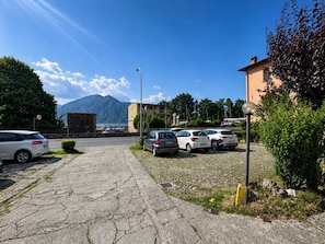 A parking area with several cars, a mountain in the background, and a building with a balcony. - Casita de la Luz (Pilzone)