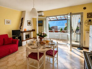 A dining area with a table set for breakfast, a red sofa, and a view of the outdoors. - Casita de la Luz (Pilzone)