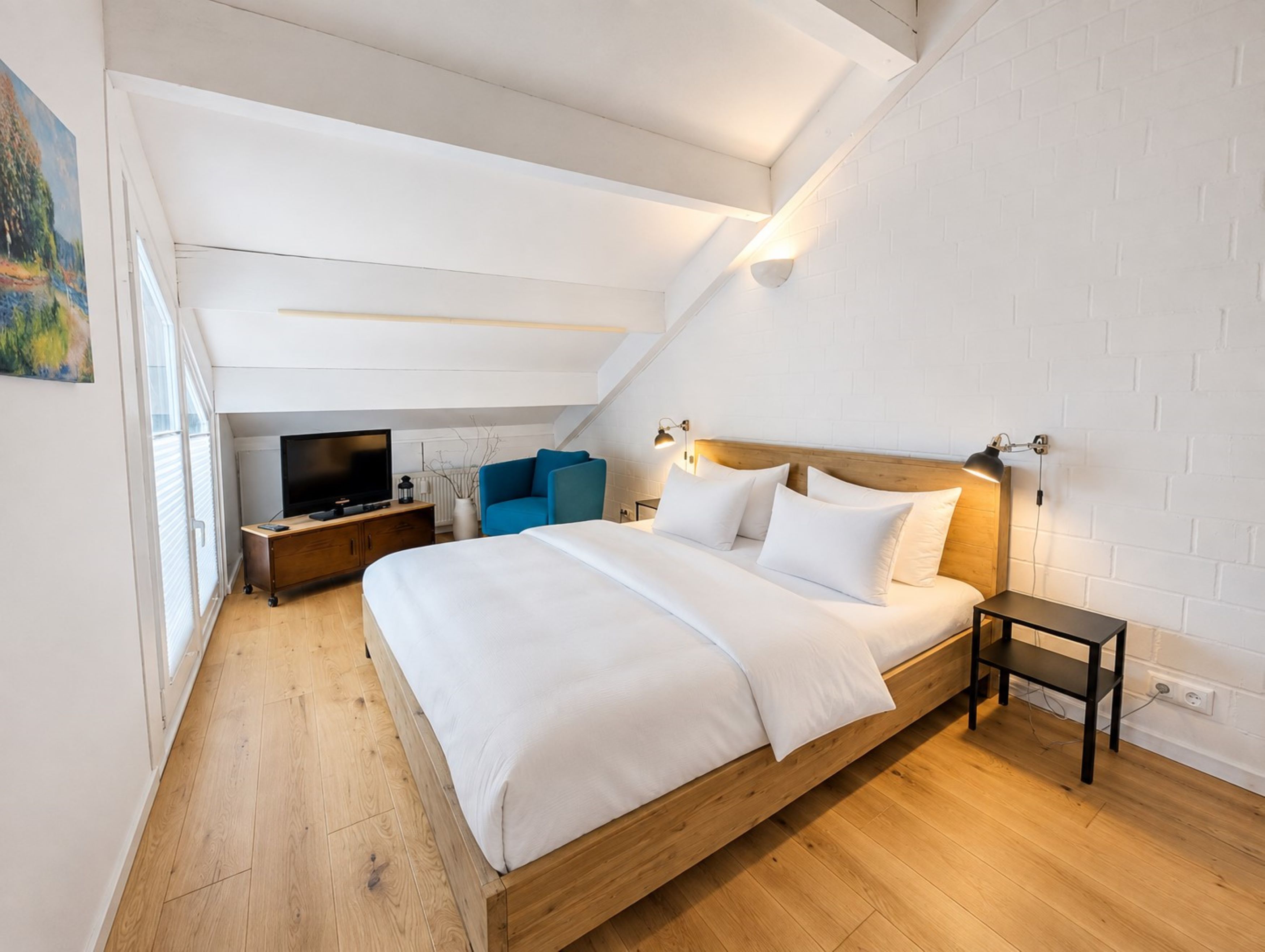 Ein Schlafzimmer mit einem Holzbett, einem Fernseher, einem blauen Sessel und einem kleinen Tisch.