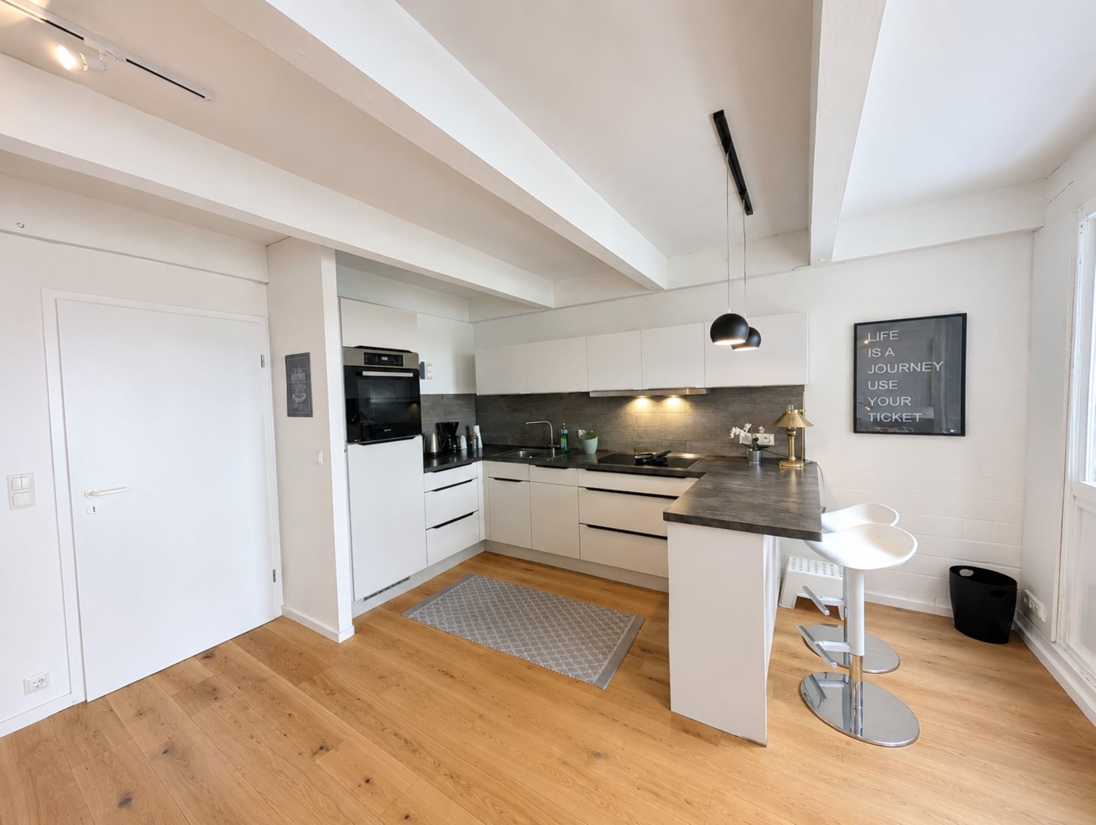 Een moderne keuken met witte kastjes, een zwart aanrecht en een ingebouwde oven.