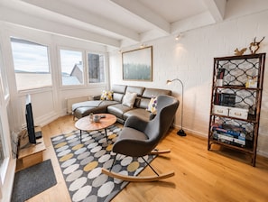 Sala de estar moderna com sofá seccional, mesa de centro, estante e vista para o exterior.