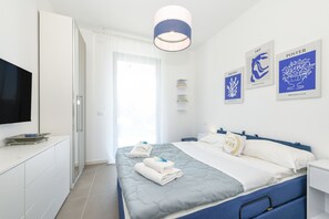 A modern bedroom with a bed, bedside tables, a TV, and artwork on the wall. - MGH - Puro Amore Apartment Lazise (Lazise)