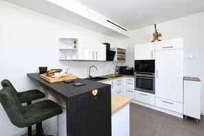 A modern kitchen with white cabinetry, a black countertop, and a built-in oven. - MGH - Puro Amore Apartment Lazise (Lazise)