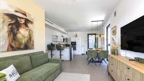 Ein modernes Wohnzimmer mit einem grünen Sofa, einem Essbereich und einer Küche.